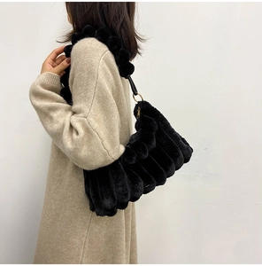 Detail of plush black shoulder bag with wave texture and gold hardware on model
