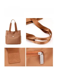 Détail du sac cabas en nylon marron montrant les coutures de la poignée et la fermeture éclair