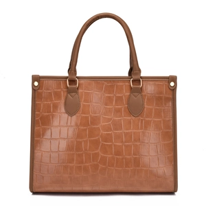 Brown crocodile embossed tote bag with gold metal rings and studs on white background