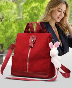 Detail view of red corduroy backpack showing vertical zipper and plush rabbit charm