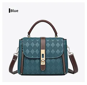Détail du sac à bandoulière matelassé bleu avec boucle dorée et poignée marron