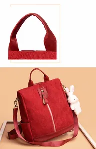 Detail view of red corduroy backpack with leather handle and cute plush bunny charm