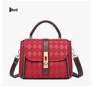 Détail du sac à main rouge en cuir matelassé avec fermoir doré et poignée marron