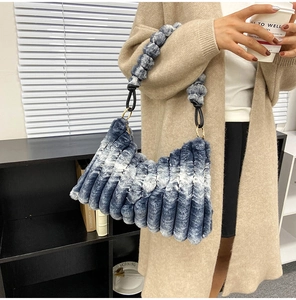 Detail of blue and white striped plush faux fur bag with fuzzy ball strap shoulder design