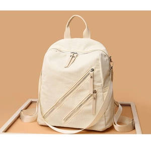 Detail of off-white corduroy backpack showing textured fabric and dual zipper pockets