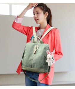 Detail of light green corduroy backpack with plush bunny charm and zip pocket