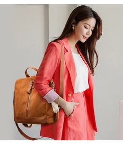 Side view of woman carrying brown corduroy backpack with leather base and plush charm