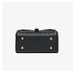 Détail du fond du sac en cuir noir avec pieds dorés et coutures blanches nettes