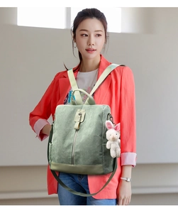 Detailed texture of green corduroy backpack featuring a cute white rabbit keychain charm