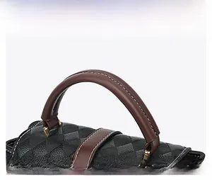 Détail du sac à main en cuir noir avec poignées marron et surpiqûres blanches