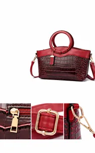 Détails des ferrures dorées et du zip en cœur sur le sac rouge à motif crocodile