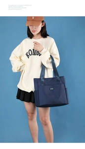 Sac fourre-tout en nylon bleu foncé porté par un mannequin sur fond bleu clair