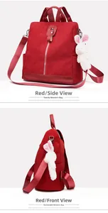 Detail view of red corduroy backpack featuring a side-hung plush rabbit keychain
