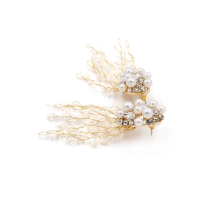 Détail de boucles d'oreilles vintage en perles dorées avec pompons et perles feuilles