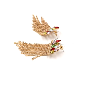 Close-up of long tassel earrings with multicolored crystals and gold rhinestone chains