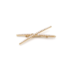 Detail view of a gold-finish X-shaped hair clip featuring elegant gradient white pearls