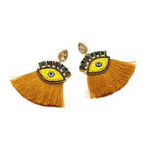 Detail of bohemian evil eye earrings with beaded accents and gold tassel fringe