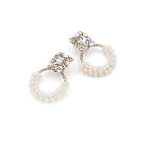 Détail de puce dorée avec diamant carré et boucles d'oreilles créoles en perles tissées
