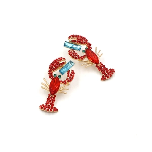 Detailed close-up of lobster earring featuring red rhinestones and blue gemstones