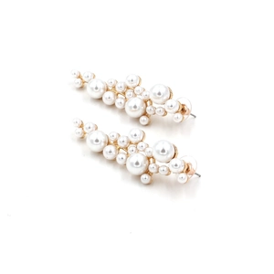 Dettaglio di orecchini pendenti con perle barocche ed elegante base in metallo dorato