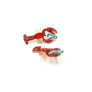 Detailed close-up of crystal lobster earrings with red rhinestones and gold plating
