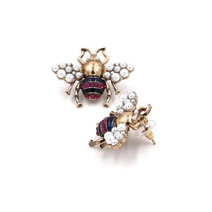 Macro detail of vintage gold bee earring with pearl wings and pink crystal accents