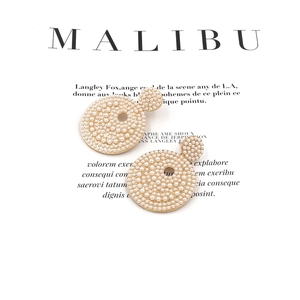 Modern baroque style gold earrings featuring clustered white pearls on a minimalist background