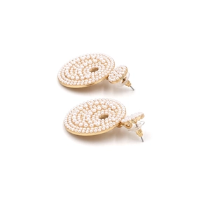 Close-up of baroque pearl drop earrings featuring pavé settings and golden metal base