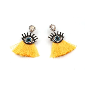 Detail showing long yellow silk tassel earrings with evil eye rhinestone and crystal charms