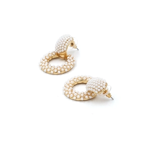 Close-up of baroque hoop earrings with white pearls pavé set in golden metal hardware