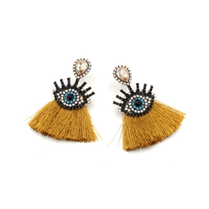 Detailed macro view of bohemian evil eye earrings with yellow fringe and inlaid gemstones