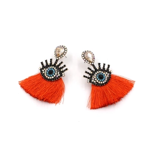 Detail of orange tassel earrings with evil eye rhinestone motif and teardrop crystal