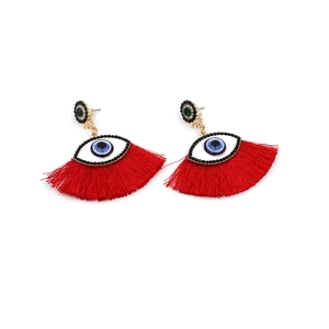 Detail of bohemian evil eye earrings with green crystal studs and vibrant red tassels