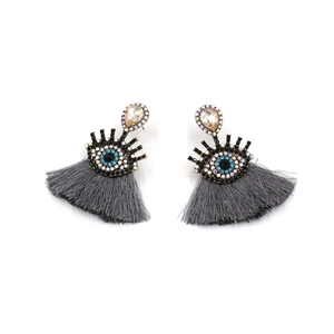Detail of bohemian evil eye earrings with crystal studs and grey silk tassels