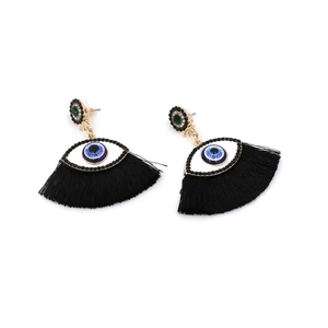 Close-up of evil eye earrings with dark blue pupils and long black silk tassels