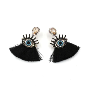 Detail of bohemian evil eye earrings featuring blue crystal charms and black silk tassels