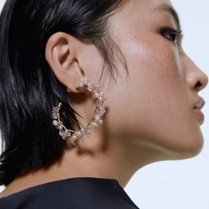 Handcrafted gold wire C-shaped earrings with pearls and crystals shown on a model