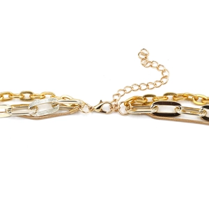 Vue macro détaillée du collier triple chaîne or et argent avec fermoir mousqueton