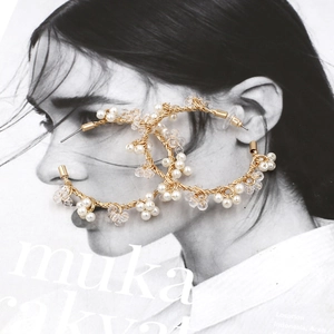 Detail of handmade gold wire hoop earrings featuring white pearls and clear crystal beads