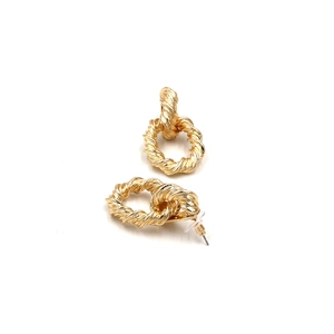 Close-up of golden twisted texture stud earrings with clear silicone backings