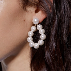 Boucles d'oreilles créoles oversize en perles blanches sur mannequin au style urbain chic