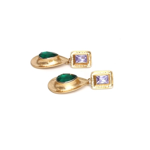 Vue détaillée de boucles d'oreilles dorées vintage avec cristaux verts et violets