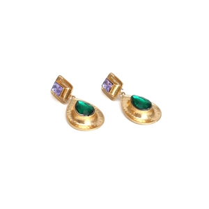 Détail de boucles d'oreilles dorées avec pierres violettes et cristaux goutte verts