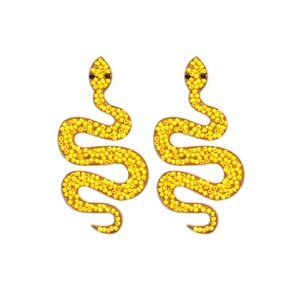 Retro serpent stud earrings with yellow beads and golden metal finish on white background