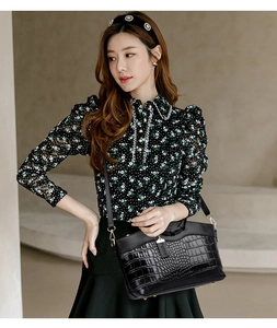 Détail du sac à main noir motif crocodile avec des finitions métalliques dorées