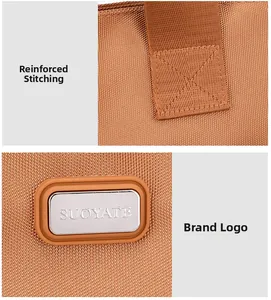 Détail de la couture en X renforcée et logo métallique argenté sur le sac en nylon brun