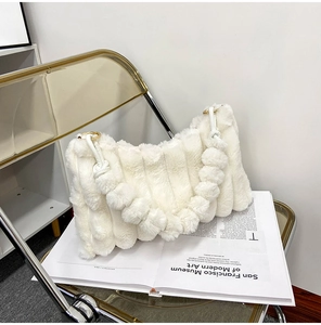 Close-up of white plush shoulder bag with textured pleats and golden hardware rings