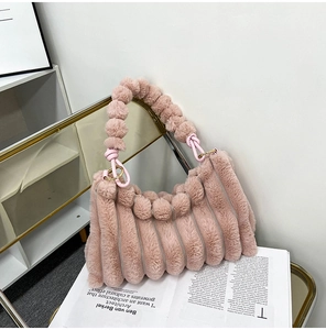 Detail of pink plush bag featuring wave textures and decorative pom-pom bead handle