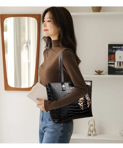 Close-up of black crocodile-textured tote bag with elegant leopard print silk scarf detail