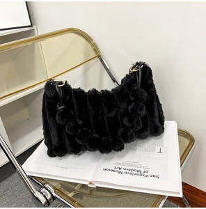 Detail view of black faux fur handbag featuring soft ripple texture and golden metal rings